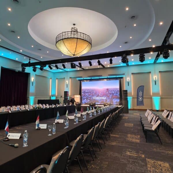 Evento formal en salón con escenario de fondo.