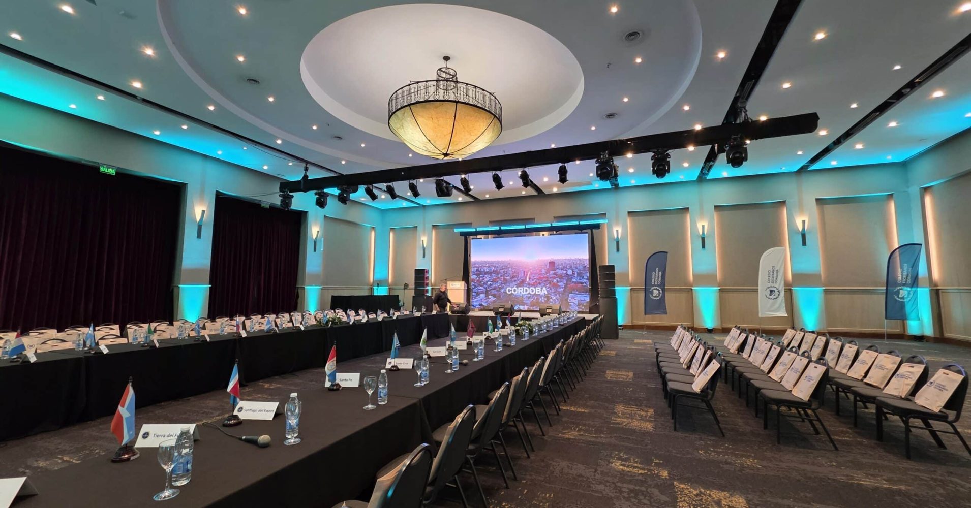 Evento formal en salón con escenario de fondo.